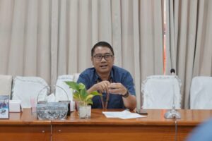 Pelaku UMKM sedang menghitung uang hasil penjualan dan mencatat transaksi di buku kas sederhana di meja usaha kecil.